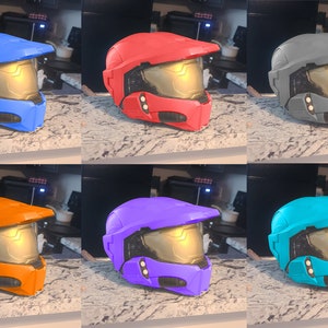 May include: Six plastic helmets in different colors: blue, red, gray, orange, purple, and turquoise. The helmets have a gold visor and black details.