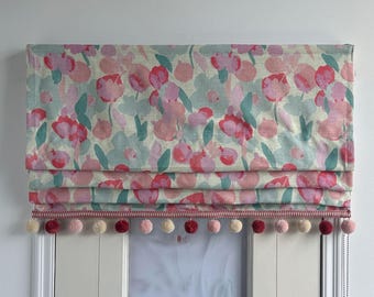 Estor romano de lino natural rosa con estampado de rosas, decorado con pompones, personalizable en tamaño, con o sin cordón.