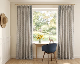Könnte beinhalten: Bodenlange Vorhänge mit Faltenwurf aus hellgrauem Stoff mit Muster und einer vertikalen blauen Bordüre im griechischen Schlüsseldesign. Die Vorhänge hängen an einer goldfarbenen Metallstange und rahmen ein Fenster mit Gartenblick ein.