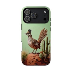 May include: A phone case featuring a detailed illustration of a roadrunner bird standing on a rock with cacti in the background. The case has a light green border and a camera cutout.