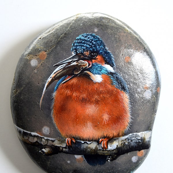 Sven, the Kingfisher< is eating a tasty fish. Painted on a large stone