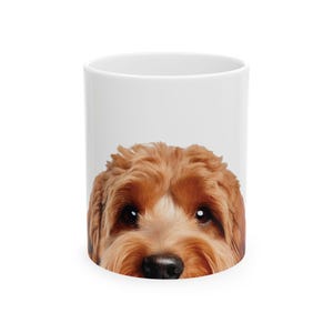 May include: A white ceramic mug with a brown and white dog's face peeking over the rim.