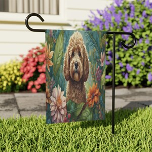 May include: A garden flag featuring a brown and white doodle dog with a floral background. The dog is surrounded by pink, orange, and purple flowers.