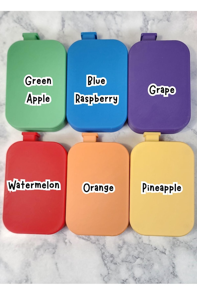 May include: Six colorful, rectangular containers with rounded corners are displayed. Each container is a different color: green, blue, purple, red, orange, and yellow. Each container has a label with a fruit name: Apple, Raspberry, Grape, Watermelon, Orange, and Pineapple.