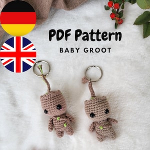 Puede incluir: Dos llaveros de Baby Groot tejidos a crochet. Cada llavero presenta una pequeña figura marrón tejida a crochet con ojos negros y detalles verdes. Los llaveros están sujetos a anillos plateados. El texto "PDF Pattern BABY GROOT" es visible.