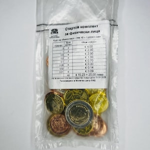 Puede incluir: Una bolsa de plástico transparente que contiene un conjunto de monedas de euro. Las monedas son de varios tamaños y colores, incluyendo oro, bronce y plata. Una etiqueta impresa con texto en un idioma extranjero es visible en la parte superior.