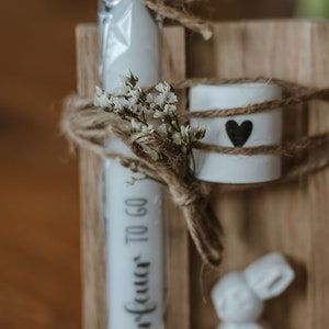 Osterkerze mit Halter und frühlingshaften Trockenblumen und kleinem Hasen für Dekoration