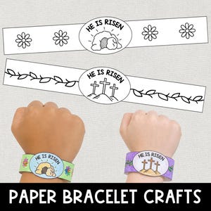 May include: Paper bracelet crafts with the text "HE IS RISEN". The bracelets feature illustrations of a tomb and crosses. One bracelet is on a wrist with a green and blue design, and the other is on a wrist with a purple design.