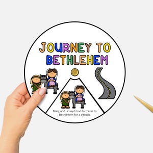以下が含まれることがあります： カラフルな文字で「JOURNEY TO BETHLEHEM」と書かれた円形のイラスト。ロバに乗ったマリアとヨセフ、道、金の円が描かれています。「Mary and Joseph had to travel to Bethlehem for a census」というテキストも含まれています。