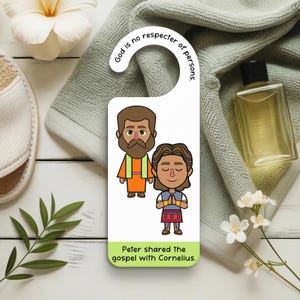 May include: A white door hanger featuring a cartoon illustration of two figures. The text "God is no respecter of persons" is at the top, and "Peter shared the gospel with Cornelius" is at the bottom. A towel and a bottle are in the background.