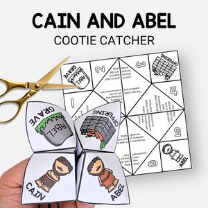 May include: A handmade paper cootie catcher with the text "Cain and Abel" and illustrations. The cootie catcher is open, revealing illustrations and text. Gold scissors are placed next to the cootie catcher.