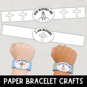 May include: Paper bracelet crafts with the phrases "God Blesses Me" and "I Am Blessed". The bracelets feature cross and heart designs. The image shows two wrists wearing the bracelets.