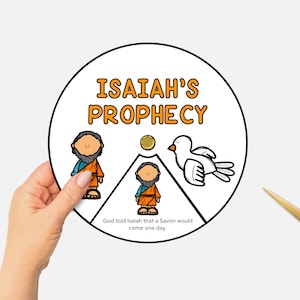 May include: A circular illustration labelled "Isaiah's Prophecy" featuring cartoon figures and a dove. The text reads, "God told Isaiah that a Saviour would come one day." A hand holds the illustration, with gold scissors in the background.