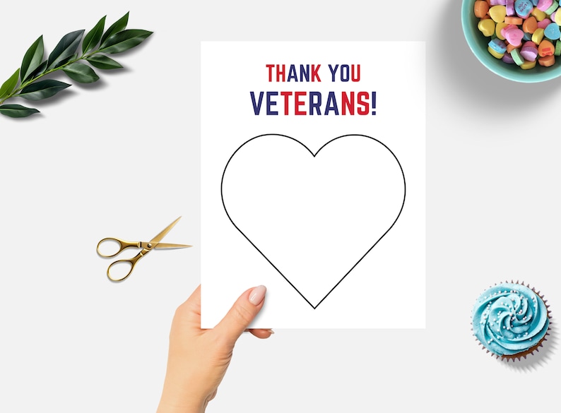 K&ouml;nnte beinhalten: Eine wei&szlig;e Karte mit schwarzer Herzumrandung und dem Text "THANK YOU VETERANS!" in Rot und Blau. Eine goldene Schere, gr&uuml;ne Bl&auml;tter, eine Sch&uuml;ssel mit Herzbonbons und ein blauer Cupcake sind ebenfalls zu sehen.