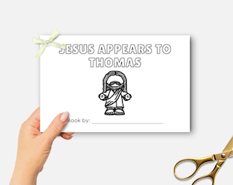 Peut inclure: Une carte blanche avec le texte "JESUS APPEARS TO THOMAS" et une illustration de Jésus. La carte est tenue par une main et a un nœud vert clair attaché. Des ciseaux dorés sont dans le coin inférieur droit.