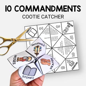 May include: A white and black "10 Commandments Cootie Catcher" with illustrations and text. A pair of gold scissors is next to the folded paper fortune teller. The text includes "Moses", "Stones", and "Kingdom".