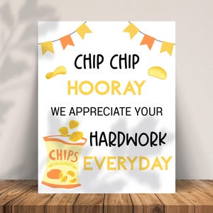 May include: A white poster with the words "Chip Chip Hooray We Appreciate Your Hardwork Everyday". The poster has a bag of chips illustration and yellow and orange banner decorations.