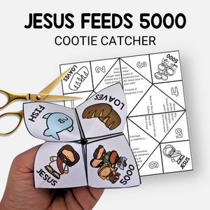 Op de afbeelding: Een witte papieren kootje vanger met de tekst "JESUS FEEDS 5000" en illustraties van vissen, brood en mensen. Gouden schaar ligt naast de kootje vanger. De kootje vanger wordt in een hand gehouden.