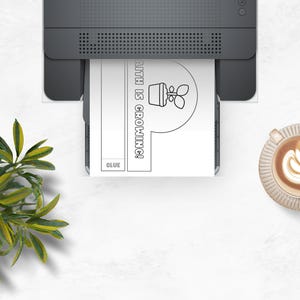 May include: A printer is shown printing a black and white image with the text "FAITH IS GROWING!" and a drawing of a plant in a pot. A cup of coffee with latte art and a plant are also visible.