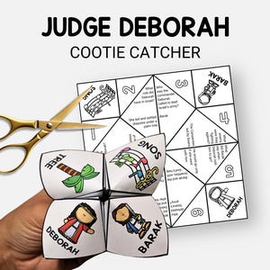 May include: A handmade "Judge Deborah" cootie catcher, with illustrations and text. The cootie catcher is held open, with gold scissors nearby. The text includes "Judge Deborah" and "Cootie Catcher".
