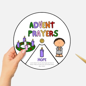 May include: A circular Advent Prayers chart with colorful text and illustrations. The chart includes a wreath with candles, a cartoon figure, and the word "HOPE". A hand holds the chart near a pair of gold scissors.