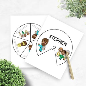 May include: Two white cards with illustrations and text. One card has a circular design with segmented illustrations and text. The other card has the name "STEPHEN" in a circle with an illustration. A gold pen rests on the card.
