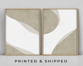 May include: Two framed prints with abstract shapes in shades of beige and white. The prints are in wooden frames and are hung on a white wall.