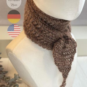 May include: A brown, textured scarf is draped on a mannequin. The scarf has a unique, open-weave design at the end. The image includes a logo with the text "PDF Pattern" and "Liven".