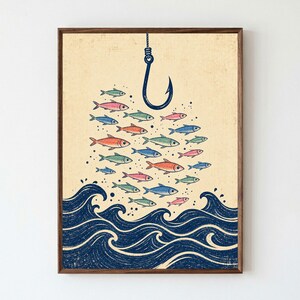 May include: A framed wall art print featuring a large blue fishing hook suspended above a school of small, multi-colored fish in shades of blue, green, and pink. Below the fish, stylized dark blue ocean waves are depicted on a cream background.