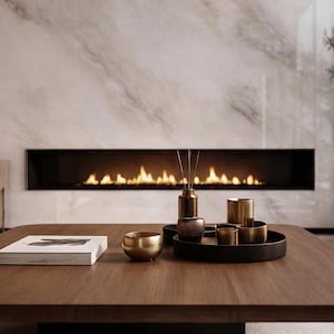 May include: A wooden coffee table displays decorative items. A gold bowl, a black tray with gold-colored cups, and a book are arranged on the table. A fireplace with flames is in the background.