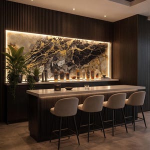May include: A modern home bar with a backlit marble backsplash and a row of liquor bottles. The bar features a light-colored countertop, four beige bar stools, and dark wood paneling. Potted plants add a touch of greenery.