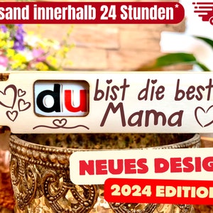 Könnte beinhalten: Holzschilder mit dem Text "du bist die beste Mama" in roten und weißen Buchstaben. Das Schild ist mit Herzen verziert und hat ein neues Design für 2024.