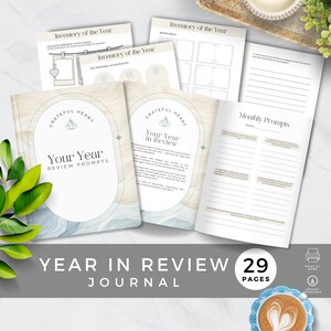 Może przedstawiać: Dziennik podsumowujący rok z niebiesko-beżowym wzorem akwarelowym. Okładka zawiera tekst "Grateful Heart" i "Your Year in Review". Dziennik ma 29 stron i zawiera pytania do refleksji i wdzięczności.