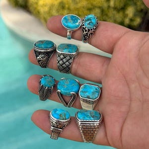 May include: A collection of silver rings, each featuring a vibrant turquoise stone. The rings showcase various designs, including ornate filigree, braided bands, and geometric settings. The turquoise stones vary in shape and size, adding to the unique appeal of each ring.