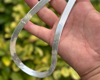 May include: A silver snake chain necklace with a shiny finish.