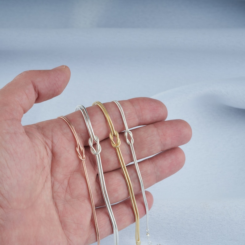 Pode incluir: Quatro pulseiras delicadas com um design de n&oacute; em prata, ouro e ouro rosa.
