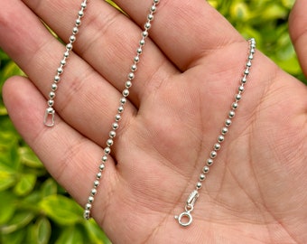 May include: A silver ball chain necklace with a lobster clasp closure.