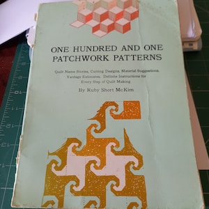 May include: A book titled "One Hundred and One Patchwork Patterns" by Ruby Short McKim. The cover features a geometric design in gold and white on a light blue background.