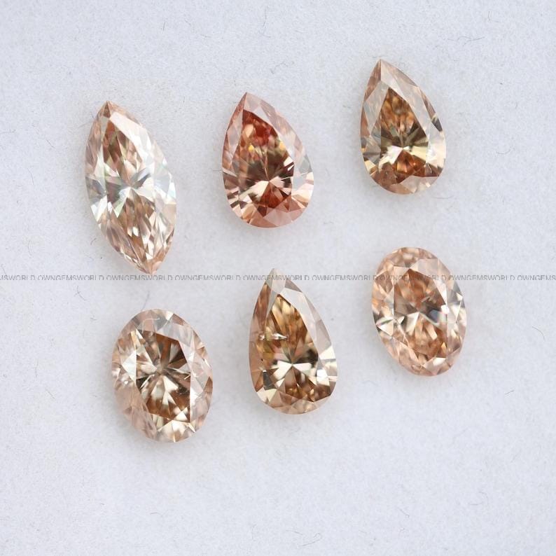 May include: Six loose faceted gemstones in various shapes, including marquise, pear, and oval cuts. These stones exhibit a warm, light brown champagne color with brilliant internal reflections and sharp, symmetrical facets throughout each piece.