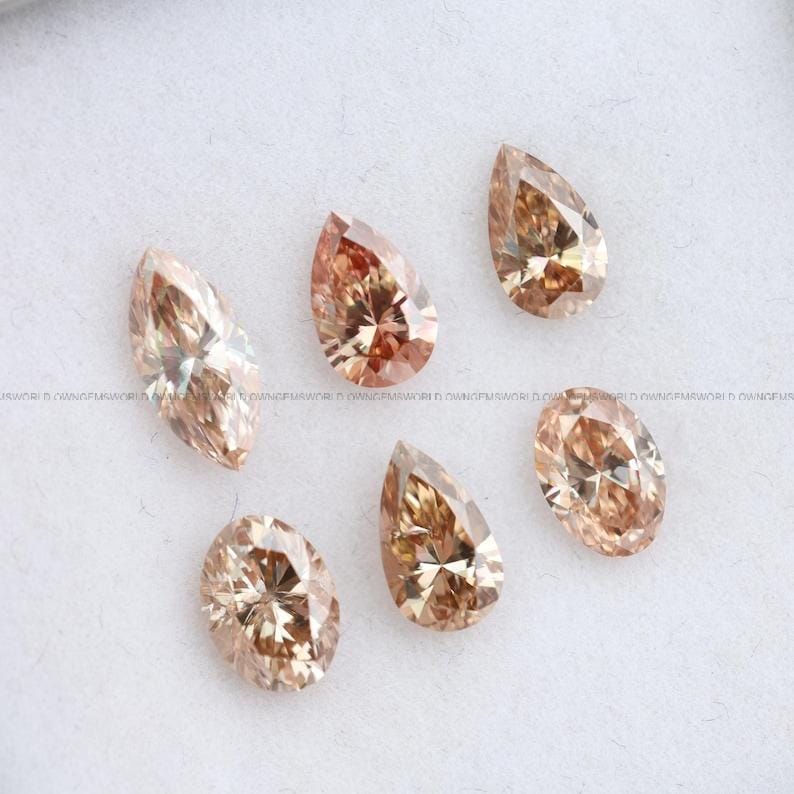 May include: Six loose faceted gemstones in shades of champagne and light brown. The collection includes one marquise cut, two pear cuts, and three oval cut stones, all displaying intricate internal light reflections and a polished, brilliant finish.
