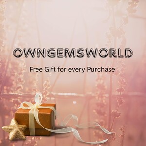 Op de afbeelding: Een bruine geschenkdoos met een gouden ster en lint op een roze achtergrond. De doos is vastgebonden met een gouden lint. De tekst "OWNGEMSWORLD" en "Free Gift for every Purchase" worden weergegeven.