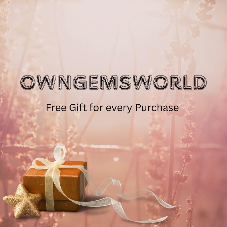 May include: A gift box with a gold star and ribbon on a soft pink background. The box is brown with a gold ribbon tied around it. The text "OWNGEMSWORLD" and "Free Gift for every Purchase" are displayed at the top.