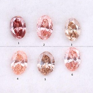 May include: Six oval-cut gemstones arranged in two rows, numbered one through six. The stones display various shades of pink, peach, and brownish-orange, each featuring a faceted surface that reflects light with a brilliant, sparkling appearance.