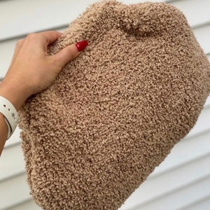 May include: A soft, brown, fluffy clutch bag made of faux fur.