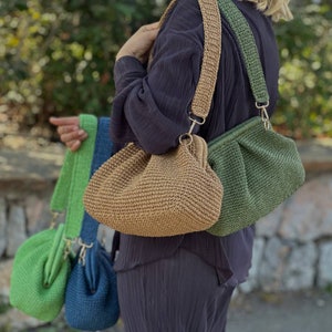 Peut inclure: Quatre sacs en crochet de diff&eacute;rentes couleurs, dont le vert, le marron et le bleu. Les sacs ont un aspect textur&eacute; et tiss&eacute; et sont port&eacute;s &agrave; l'&eacute;paule avec une longue bandouli&egrave;re.