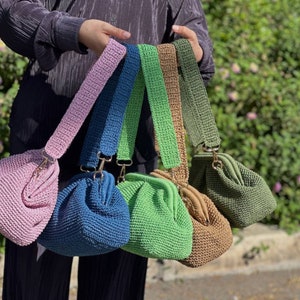 Peut inclure: Cinq sacs &agrave; main en crochet de diff&eacute;rentes couleurs, dont rose, bleu, vert, marron et vert olive. Chaque sac a un fermoir dor&eacute; et une bandouli&egrave;re en crochet.