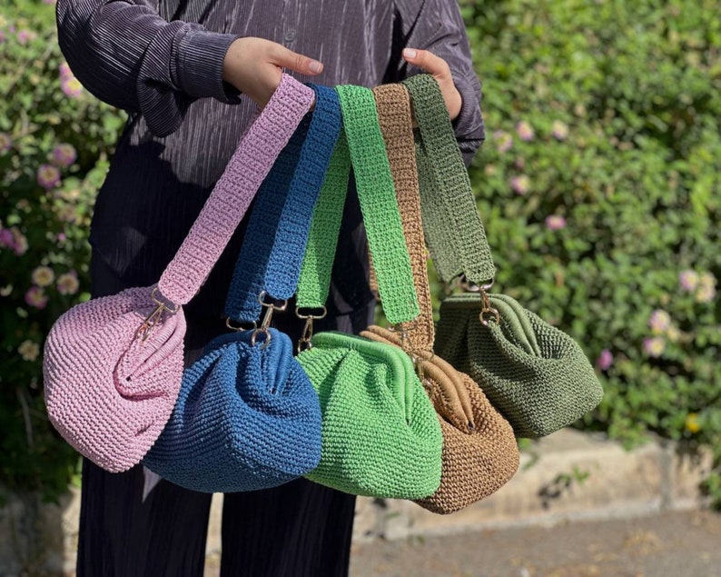 Peut inclure: Cinq sacs &agrave; main en crochet de diff&eacute;rentes couleurs, dont rose, bleu, vert, marron et vert olive. Chaque sac a un fermoir dor&eacute; et une bandouli&egrave;re en crochet.