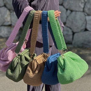 Peut inclure: Cinq sacs &agrave; main en crochet de diff&eacute;rentes couleurs, dont rose, vert, marron, bleu et vert clair. Chaque sac a une bandouli&egrave;re en crochet unique.