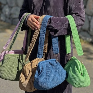 Peut inclure: Cinq sacs &agrave; main en crochet de diff&eacute;rentes couleurs, dont le vert, le bleu, le marron et le rose. Chaque sac a une bandouli&egrave;re en crochet unique et un fermoir dor&eacute;.