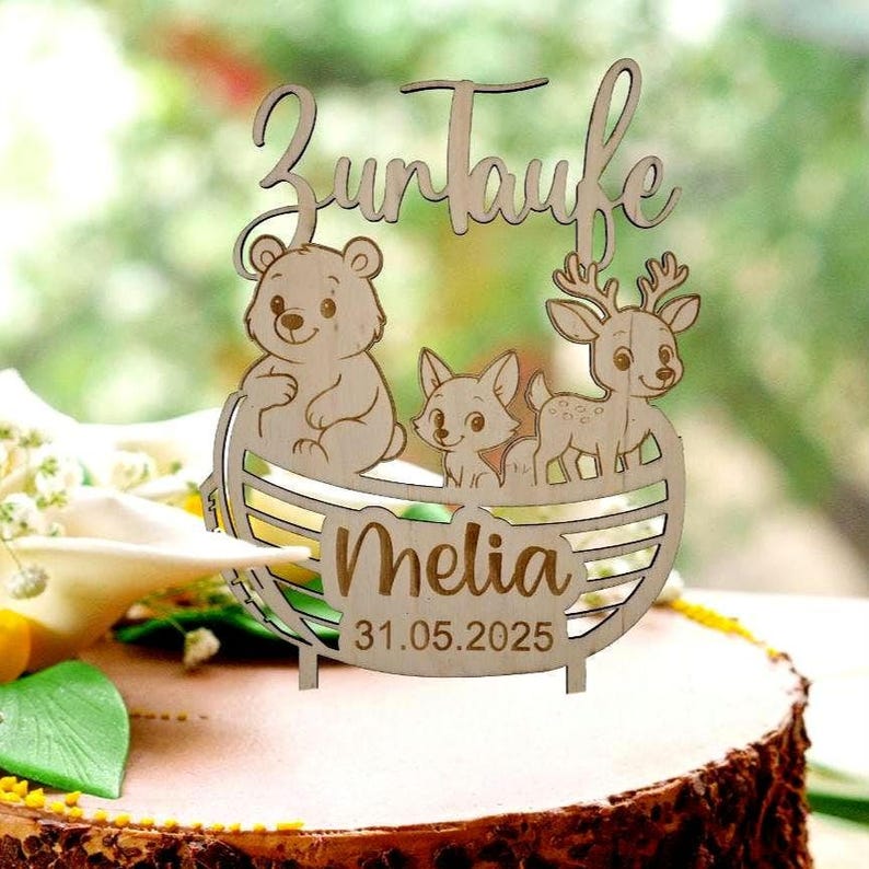 Pu&ograve; includere: Topper per torta in legno con le parole "Zur Taufe" e il nome "Melia" con la data 31.05.2025. Il topper presenta un orso, una volpe e un cervo in una barca di legno.